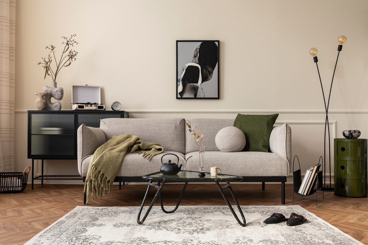 Modern living room with a light gray sofa, glass coffee table, abstract wall art, floor lamp, and minimalist decor in neutral tones.
